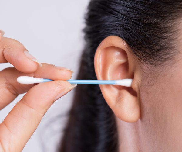 Close up young asian woman cleaning ear with cotton swab. Healthcare and ear cleaning concept.