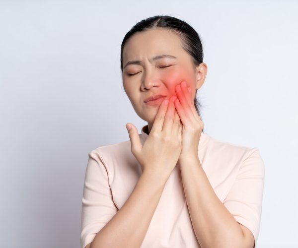 Asian woman was sick with toothache touching her cheek with red point and standing isolated on white background.