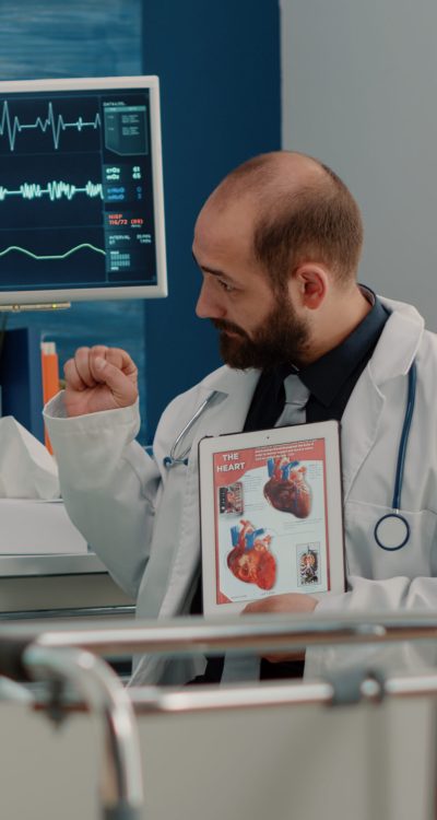 Doctor showing cardiovascular image on tablet to ill patient in hospital bed. Senior woman with sickness looking at cardiology figure with blood vessel on display for diagnosis.