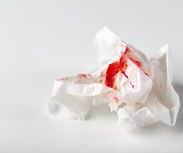 Fresh red blood stained on tissue paper on white table.