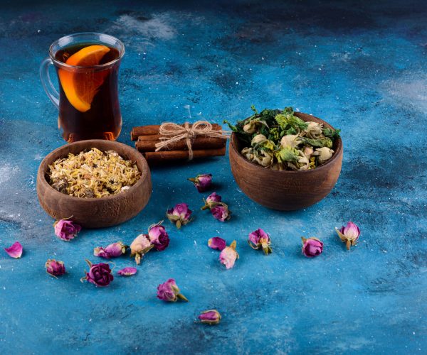 Glass of hot tea with dried flowers on blue background. High quality photo