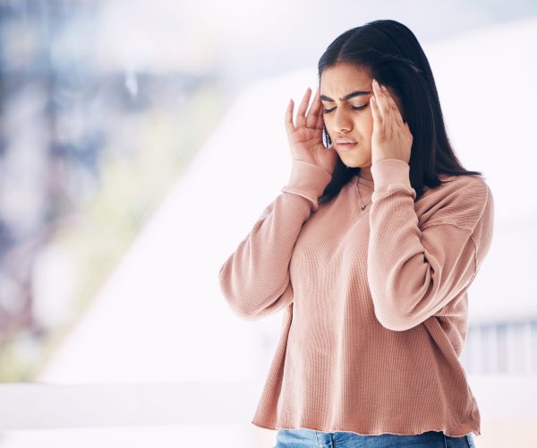 Headache, burnout or mockup with an indian woman on a blurred background suffering from pain or stress. Compliance, mental health or anxiety and a frustrated young female struggling with a migraine.