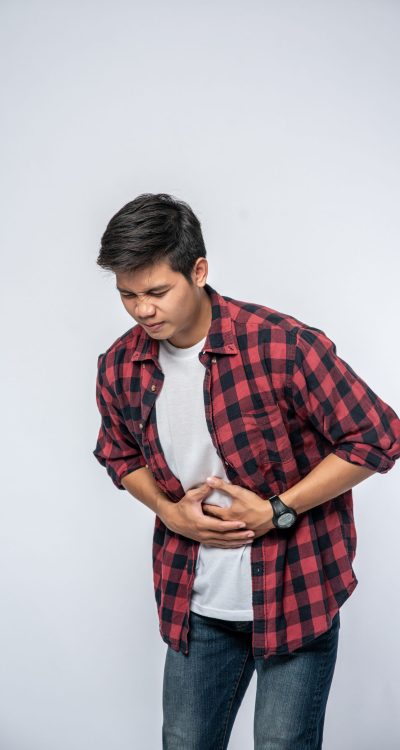 A man stands with a stomachache and puts his hand on his stomach.