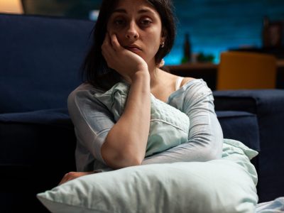 Portrait of sad person with depression problems in living room, sitting on floor and having suicidal thoughts. Depressed anxious woman in pain having mental health difficulties.