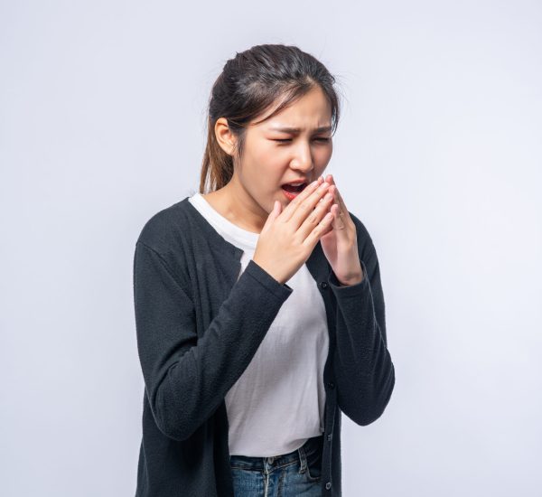 A woman coughing and covering her mouth with her hand