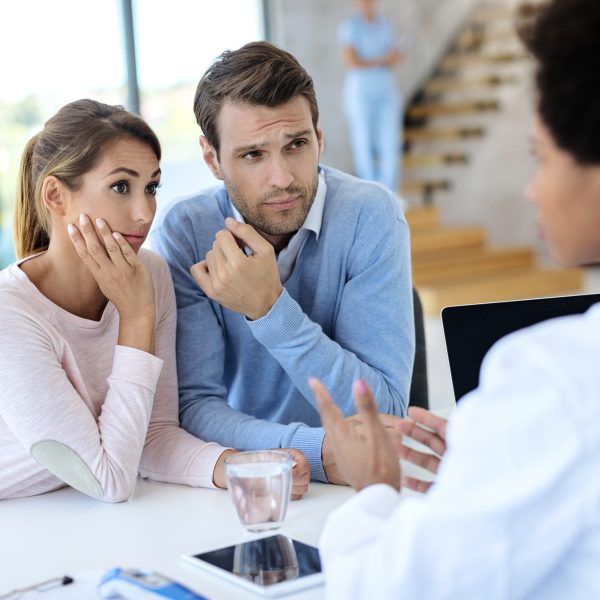 Worried couple listening to a doctor while having appointment at medical clinic.