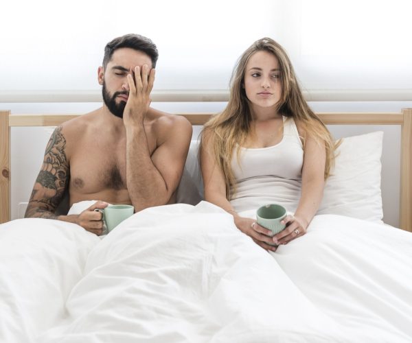 young-couple-with-cup-coffee-sitting-bed